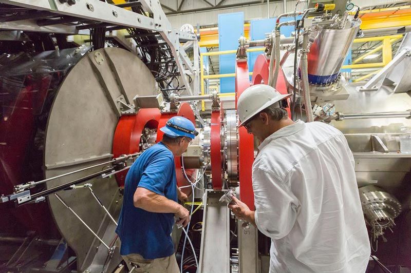 Two men, in hardhats, working on the fusion reactor.