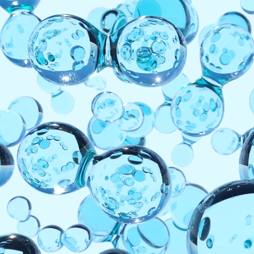 Digitally generated image of transparent blue hydrogen atoms against white background. 