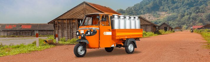 Electric three-wheeled cargo vehicle in rural setting. 