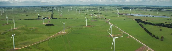 Aerial view of large wind farm over grassy fields. 